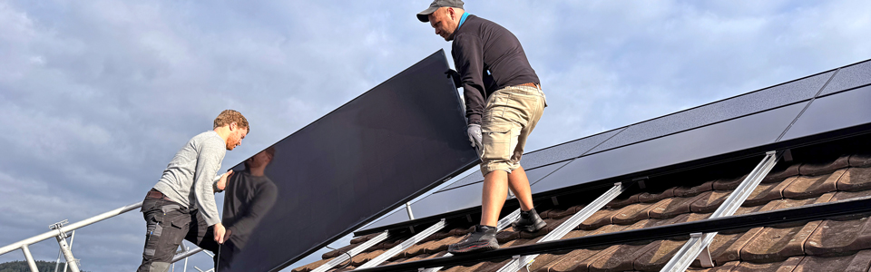 Zwei Läbesruum-Mitarbeiter montieren Solarpanels auf einem Dach in Winterthur.