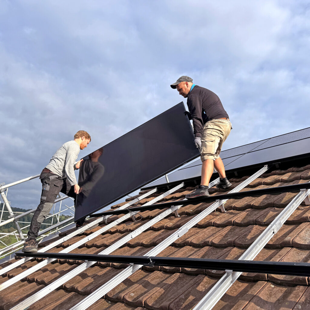 Zwei Läbesruum-Mitarbeiter montieren Solarpanels auf einem Dach in Winterthur.